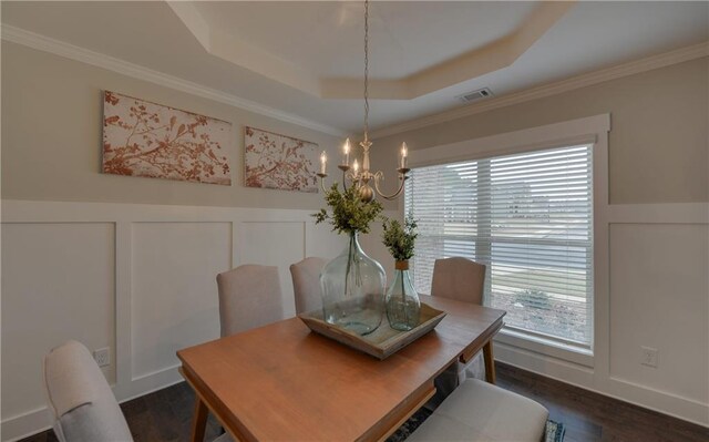 dining room with a raised ceiling, ornamental molding, dark wood-type flooring, and a notable chandelier