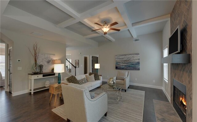 living room featuring a large fireplace, dark hardwood / wood-style flooring, beam ceiling, and coffered ceiling