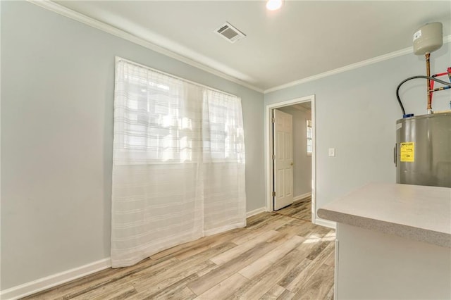 unfurnished dining area featuring ornamental molding, electric water heater, and light wood-type flooring