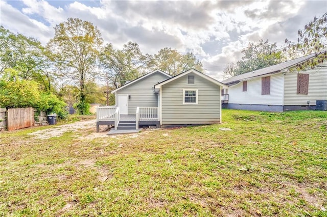 back of property featuring a deck and a lawn