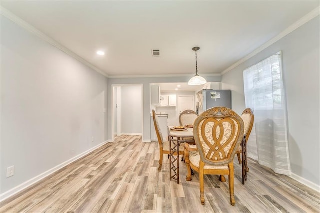 dining area with ornamental molding and light wood-type flooring