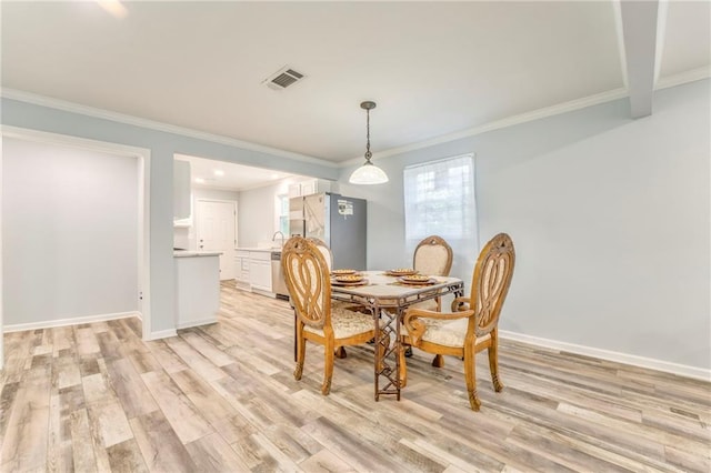 dining space featuring ornamental molding, sink, and light hardwood / wood-style floors