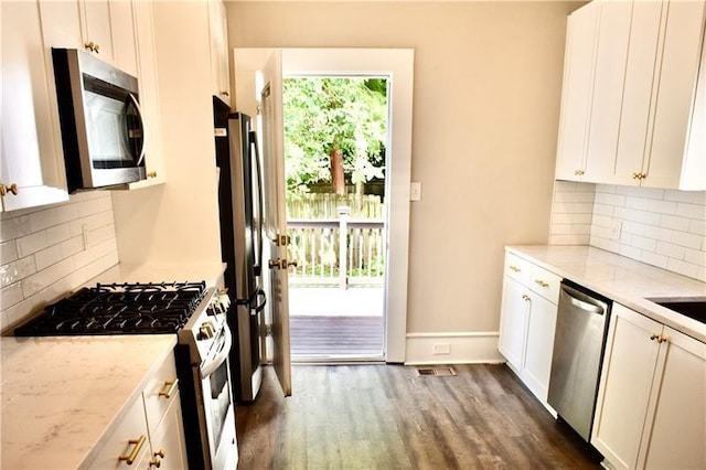 kitchen with white cabinets, appliances with stainless steel finishes, light stone countertops, and dark hardwood / wood-style floors