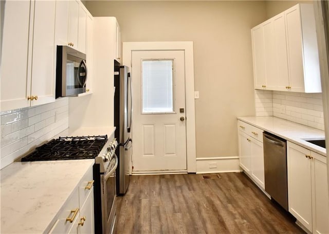 kitchen featuring white cabinets, stainless steel appliances, dark wood-type flooring, and light stone countertops