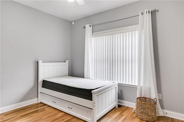 unfurnished bedroom with ceiling fan, light wood-style flooring, and baseboards