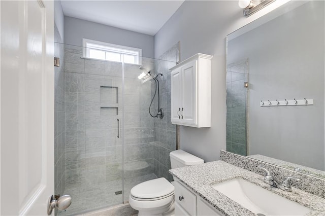 bathroom featuring a shower stall, toilet, and vanity