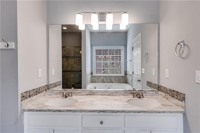 full bathroom featuring a garden tub, double vanity, backsplash, and a sink