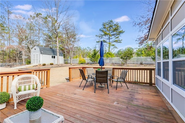 wooden deck with a storage shed, outdoor dining space, an outdoor structure, and fence