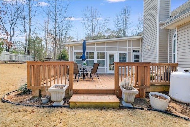 wooden deck with a sunroom, fence, and outdoor dining space