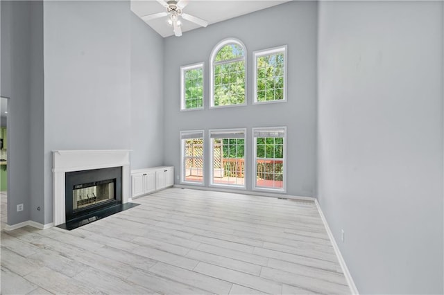 2595 Glaramara Ter, Cumming, GA 30041 - unfurnished living room with a high ceiling, a ceiling fan, wood finished floors, a fireplace with flush hearth, and baseboards