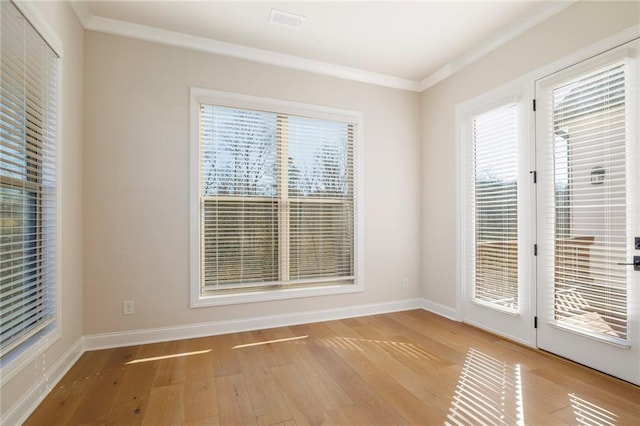 empty room with ornamental molding and light hardwood / wood-style flooring