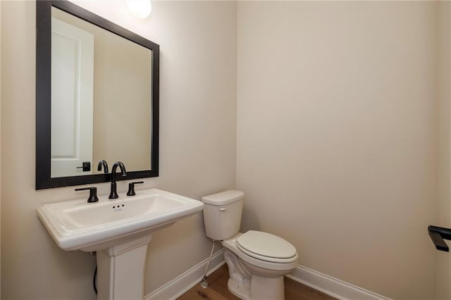 bathroom with toilet, wood-type flooring, and sink