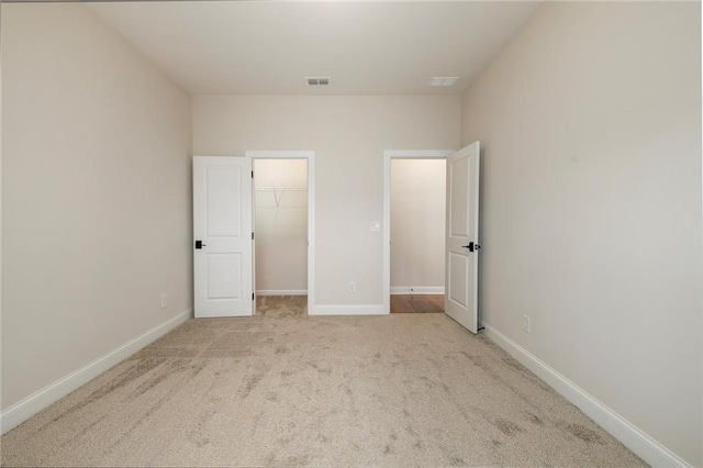 unfurnished bedroom featuring light colored carpet, a closet, and a walk in closet