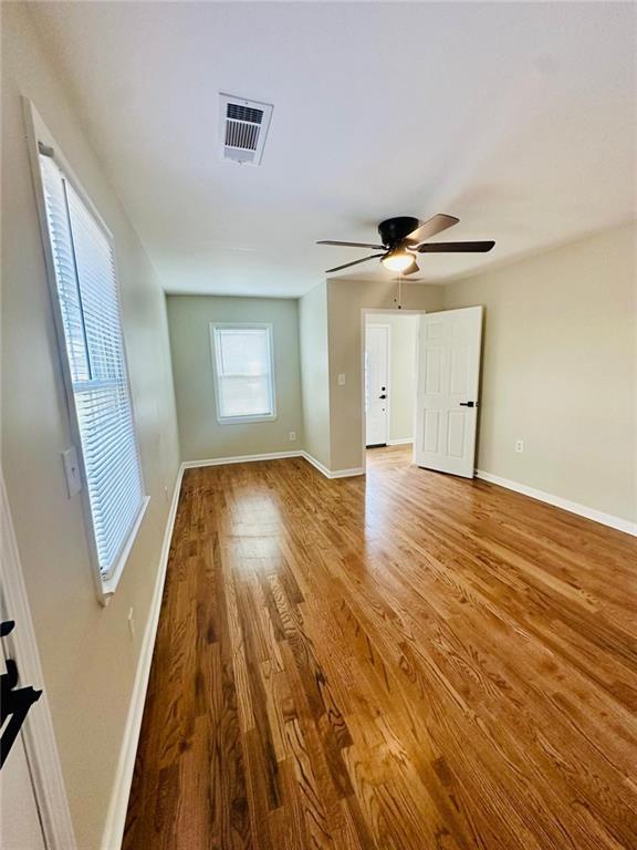 unfurnished room featuring ceiling fan, wood finished floors, visible vents, and baseboards