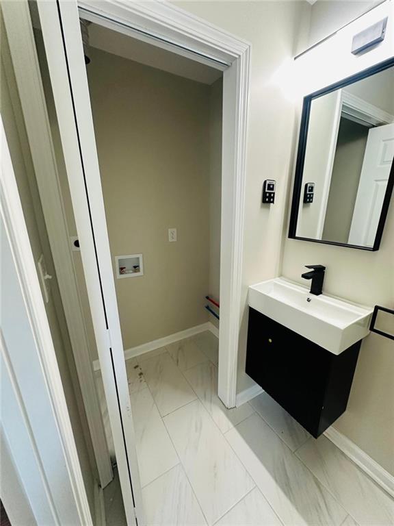 bathroom with marble finish floor, vanity, and baseboards