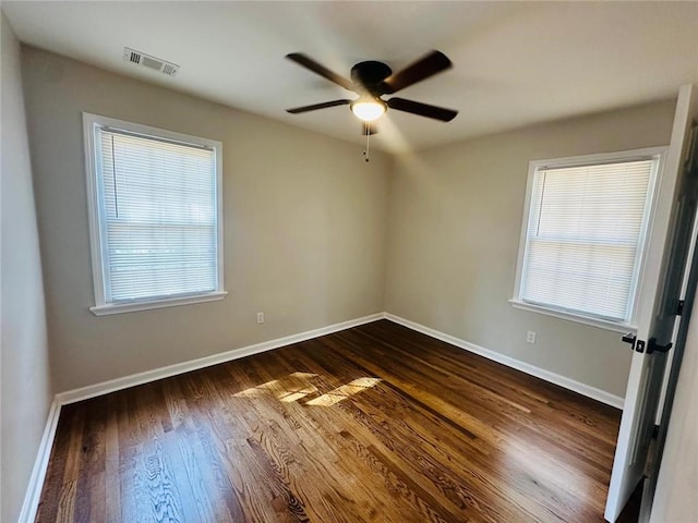 empty room featuring baseboards, visible vents, ceiling fan, and dark wood-type flooring