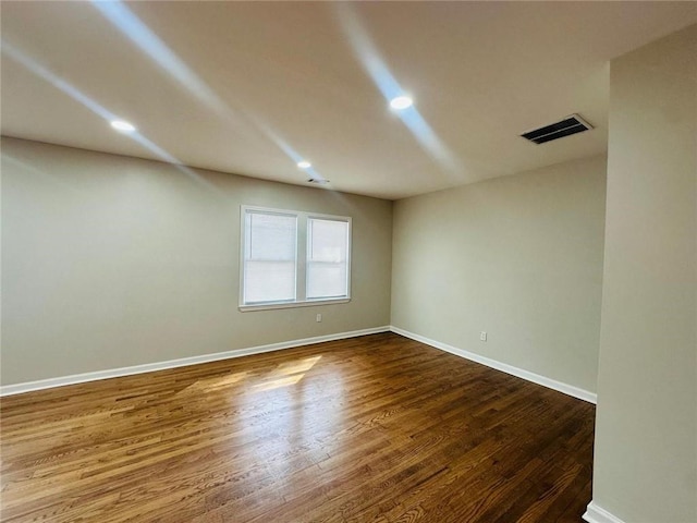 empty room with baseboards, visible vents, dark wood-style flooring, and recessed lighting