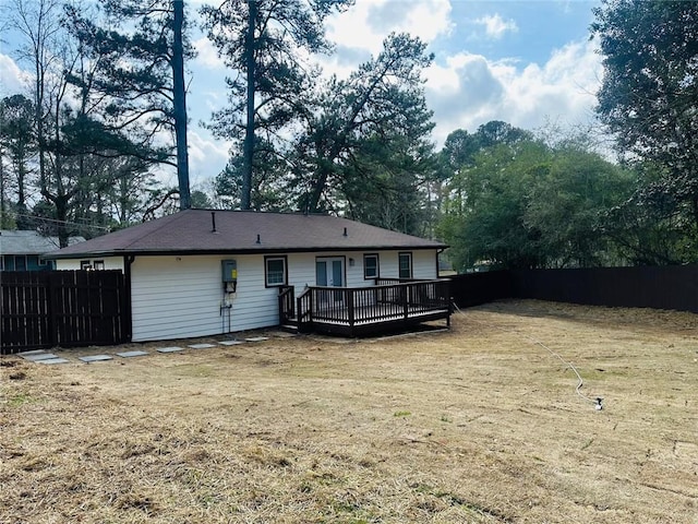 back of property with fence, a deck, and a yard