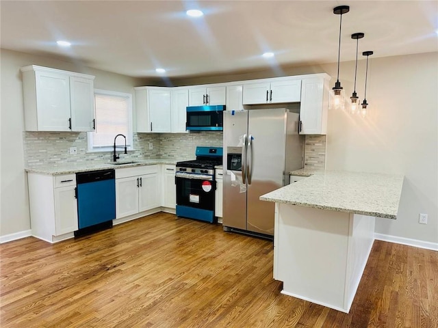 kitchen featuring light wood-style flooring, appliances with stainless steel finishes, white cabinetry, a sink, and a peninsula