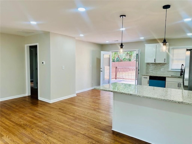 kitchen featuring tasteful backsplash, white cabinets, dishwasher, and light wood-style flooring