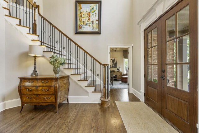 entrance foyer with stairway, a high ceiling, wood finished floors, french doors, and baseboards