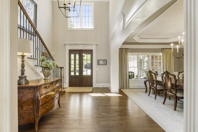 foyer with a wealth of natural light, a notable chandelier, and wood finished floors