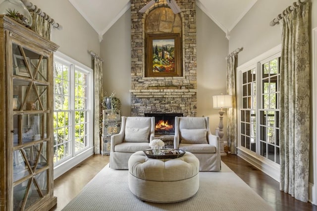 sitting room featuring crown molding, wood finished floors, a stone fireplace, and plenty of natural light
