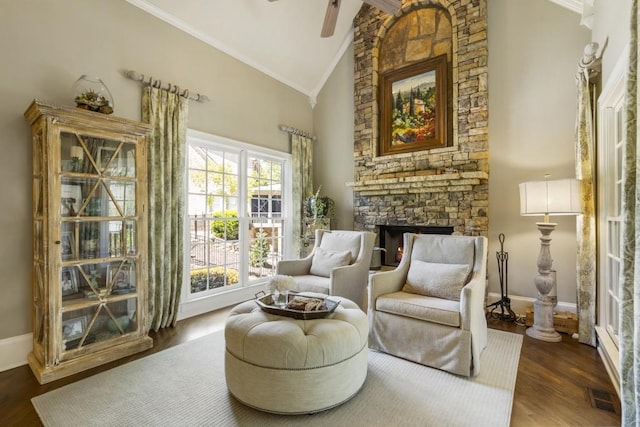 living area featuring a stone fireplace, visible vents, crown molding, and high vaulted ceiling