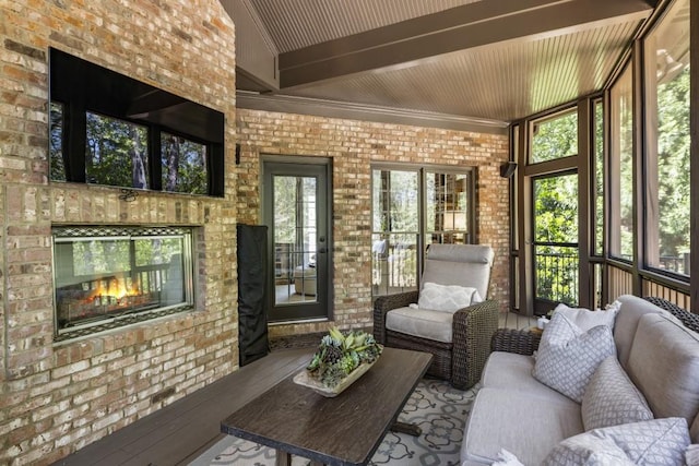 sunroom / solarium with beamed ceiling and an outdoor living space with a fireplace