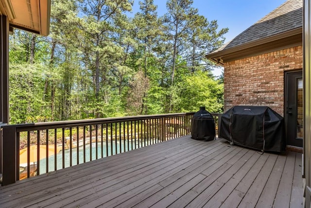 wooden terrace with an outdoor pool and area for grilling
