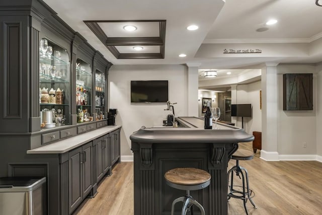 bar featuring indoor wet bar, baseboards, light wood-style flooring, and crown molding
