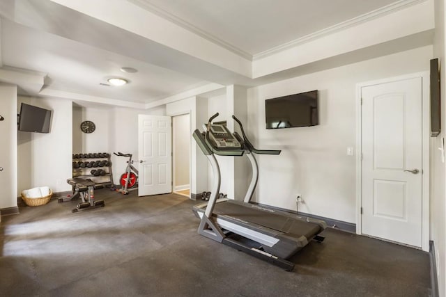 exercise area featuring baseboards, a raised ceiling, and ornamental molding