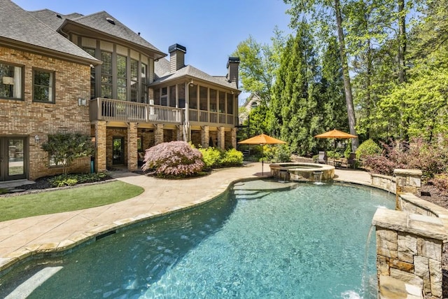 view of pool featuring a patio area, a sunroom, and a pool with connected hot tub
