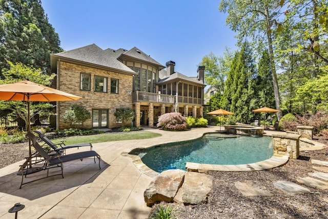 view of pool featuring a sunroom, french doors, a patio area, and a pool with connected hot tub