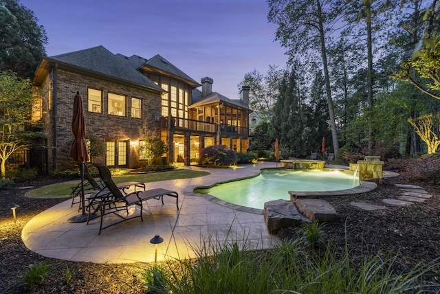 pool at dusk with an outdoor pool and a patio area