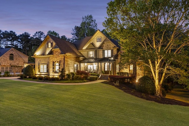 craftsman house featuring a lawn, a porch, and stone siding