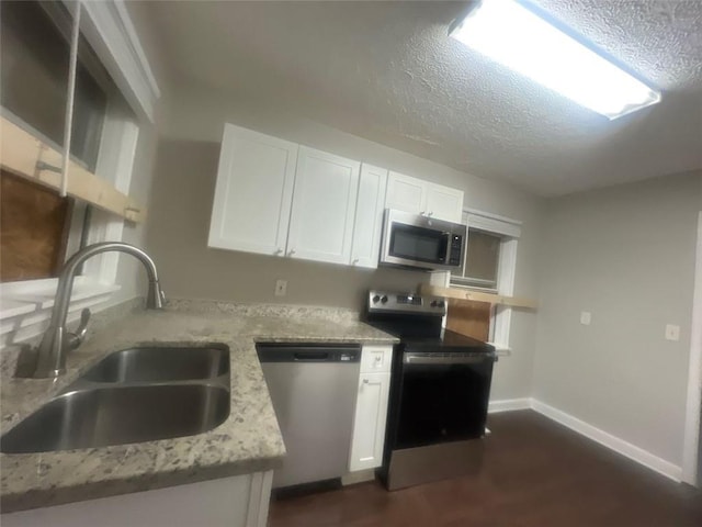 kitchen with light stone countertops, sink, a textured ceiling, white cabinets, and appliances with stainless steel finishes