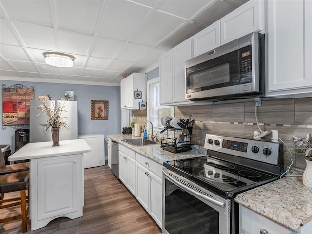 kitchen with dark wood-style floors, stainless steel appliances, decorative backsplash, white cabinetry, and a sink