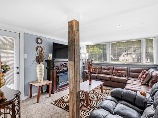 living area featuring light carpet, ornate columns, and a glass covered fireplace