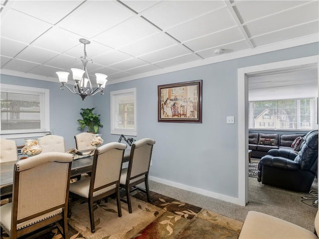 carpeted dining room featuring a notable chandelier and baseboards