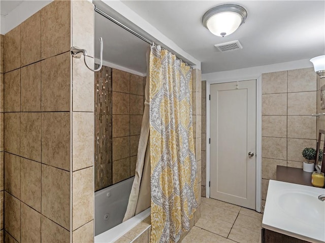 full bathroom featuring visible vents, tiled shower / bath combo, tile patterned flooring, vanity, and tile walls