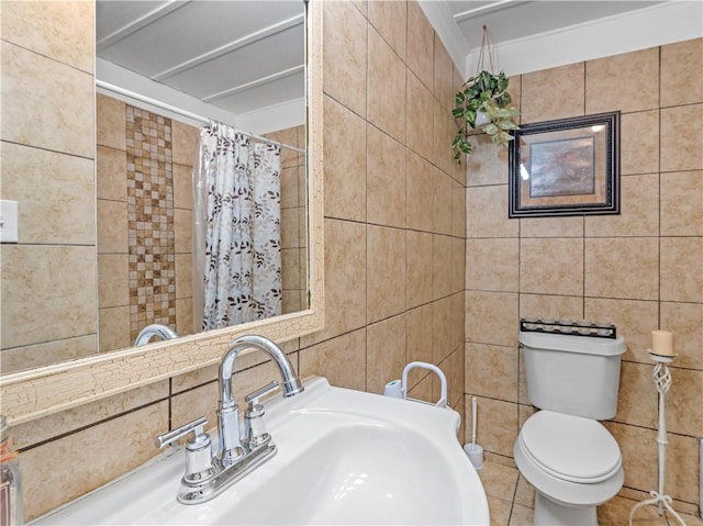 bathroom with toilet, curtained shower, a sink, and tile walls