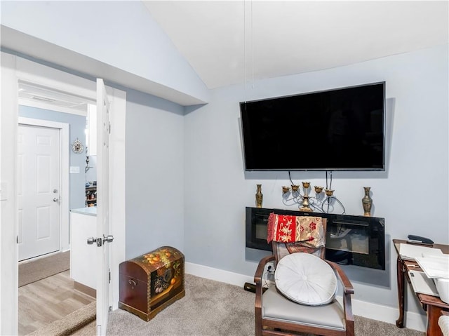 living area featuring lofted ceiling, light colored carpet, and baseboards