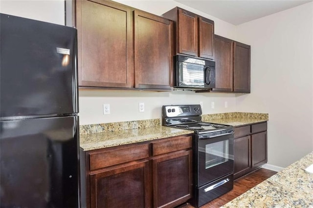 kitchen with light stone counters, black appliances, dark hardwood / wood-style floors, and dark brown cabinetry