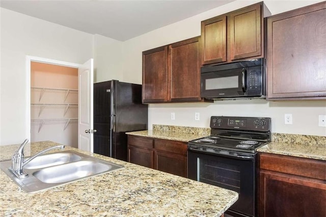 kitchen featuring sink, light stone counters, and black appliances