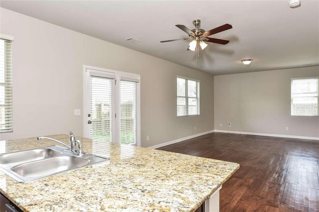 kitchen with ceiling fan, dark hardwood / wood-style flooring, sink, and a center island with sink