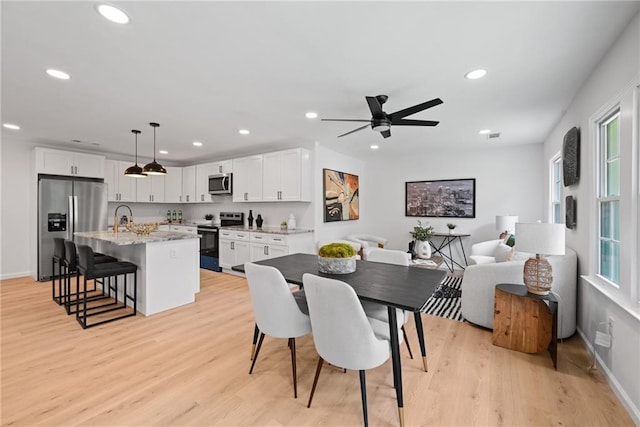 dining room featuring light wood-type flooring, ceiling fan, and sink