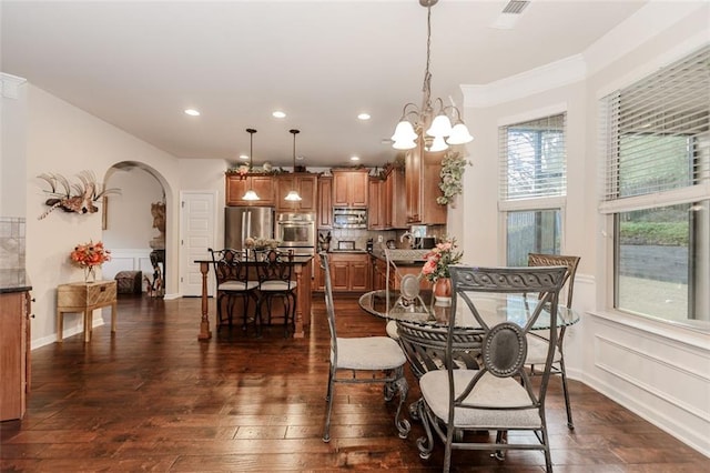 dining space featuring ornamental molding, dark wood-type flooring, and a notable chandelier