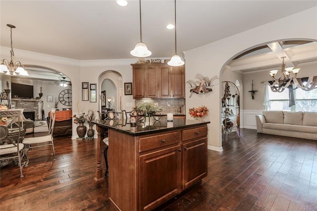 kitchen with a center island, a kitchen bar, a fireplace, decorative light fixtures, and dark hardwood / wood-style flooring