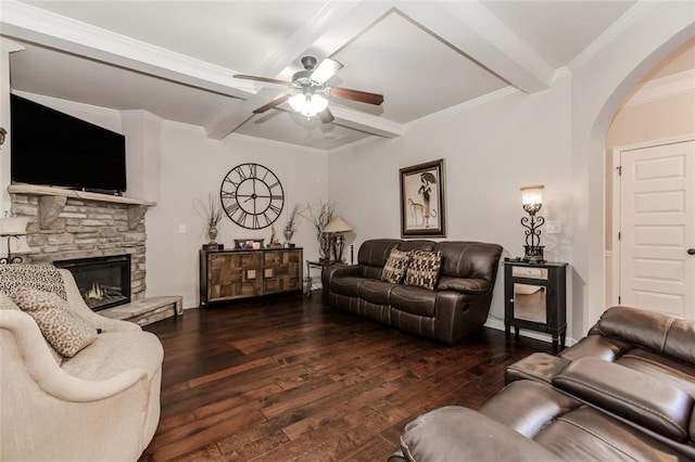 living room featuring dark wood-type flooring, crown molding, ceiling fan, a fireplace, and beamed ceiling